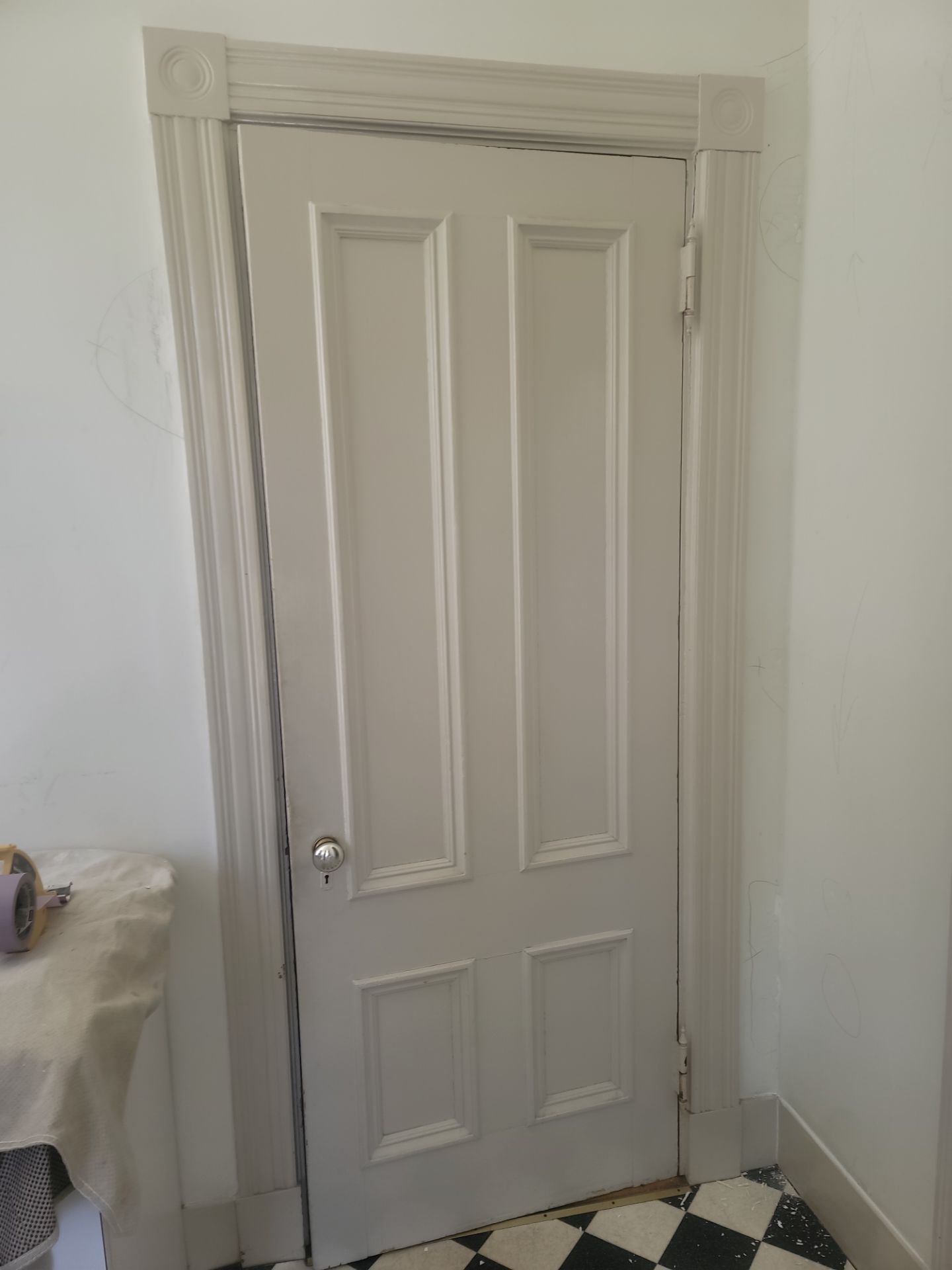 Closed white paneled door in a small room with white walls and tiled floor