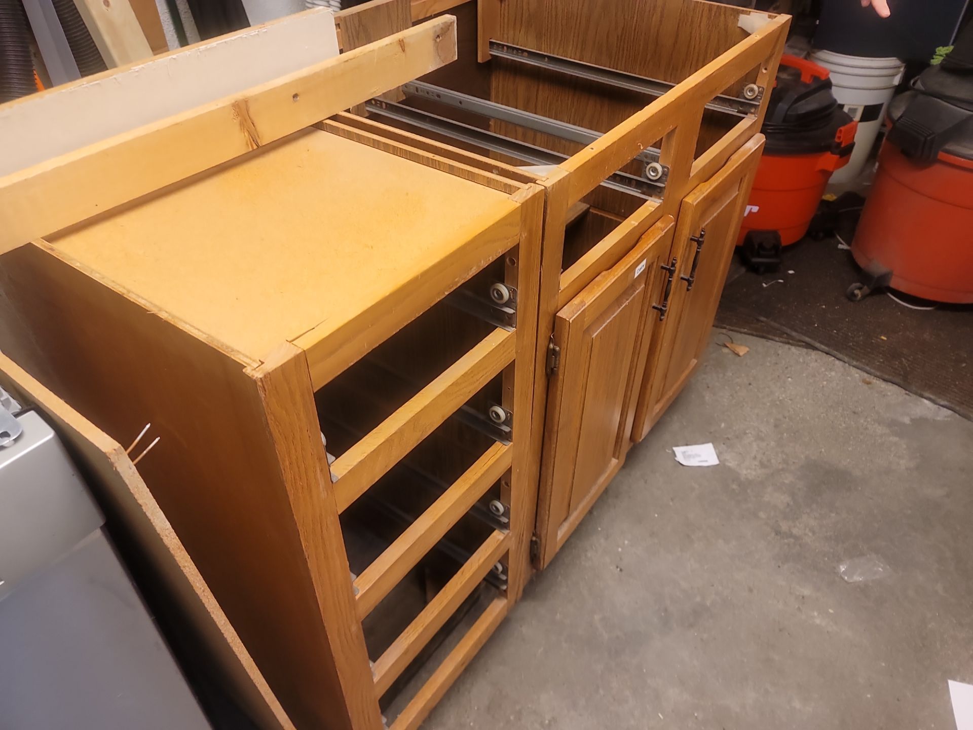 Wooden kitchen cabinet drawers and shelving units stacked in a garage or workshop.