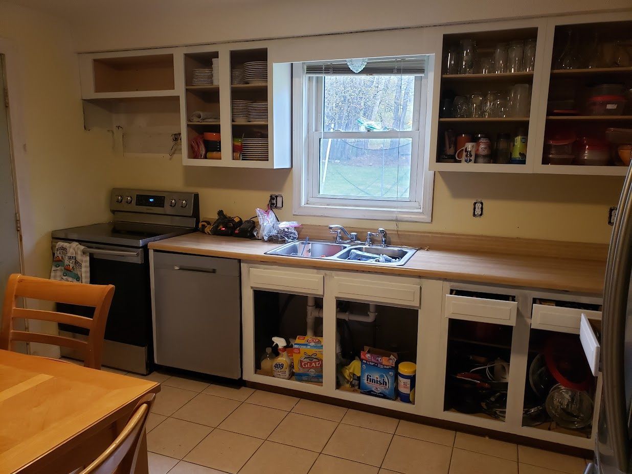 Kitchen with beige cabinets, tiled floor, sink under window, and dining table in the foreground