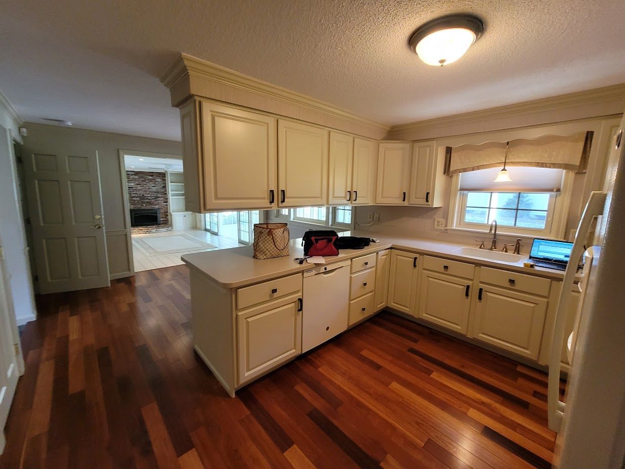 Bright kitchen with cream cabinets, hardwood floor, and a window over the sink