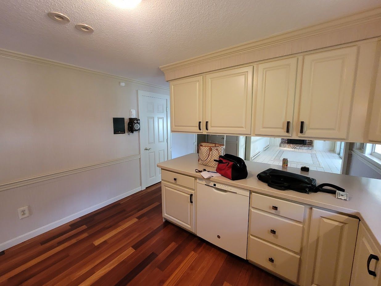 Built-in cream cabinets and countertop in a hardwood-floored room with white walls and a door.
