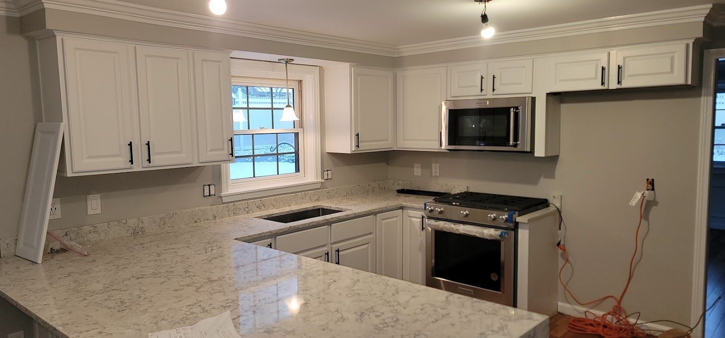 Bright modern kitchen with white cabinets, granite island, stainless steel appliances, and tile floor