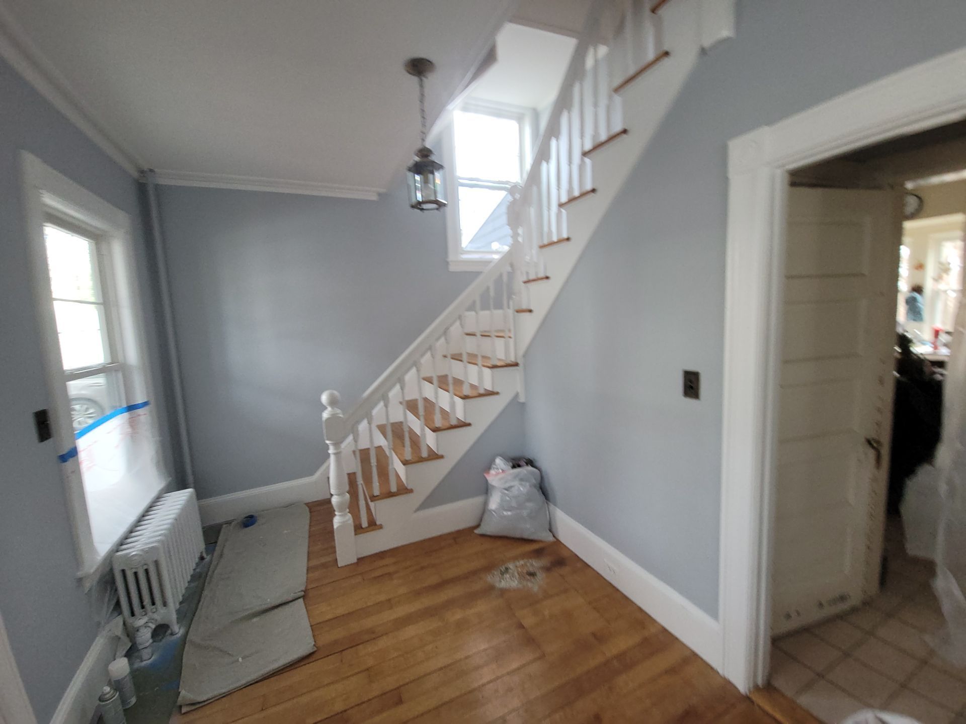 Interior hallway with wooden staircase, gray walls, and tiled entryway.