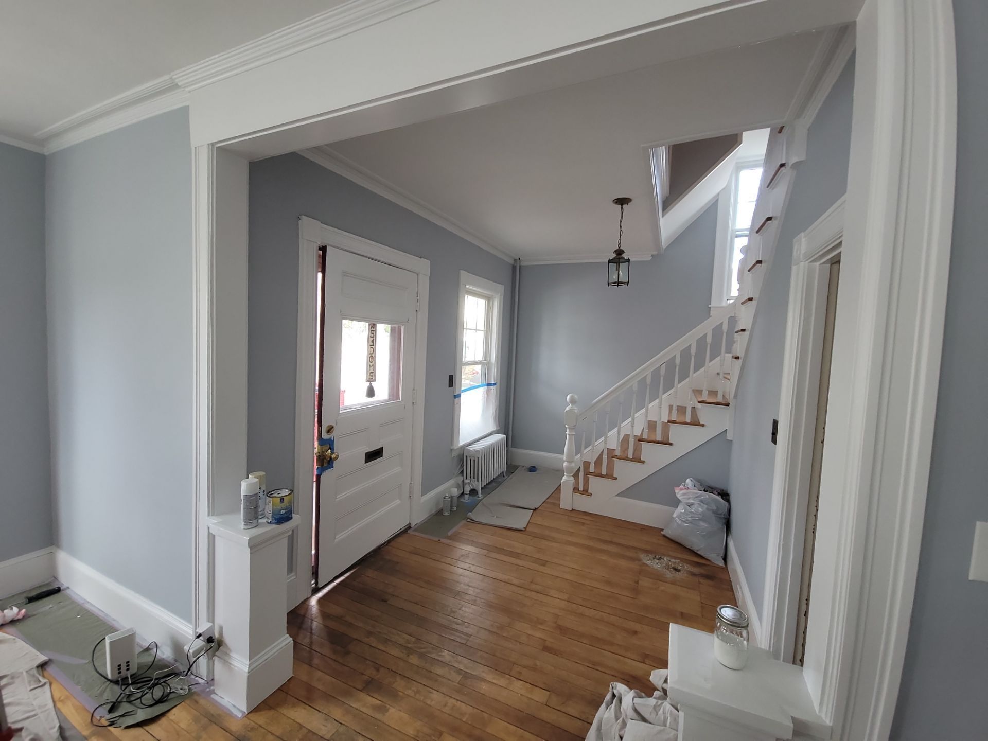 Bright entryway with gray walls, hardwood floor, staircase, and front door in a home interior.
