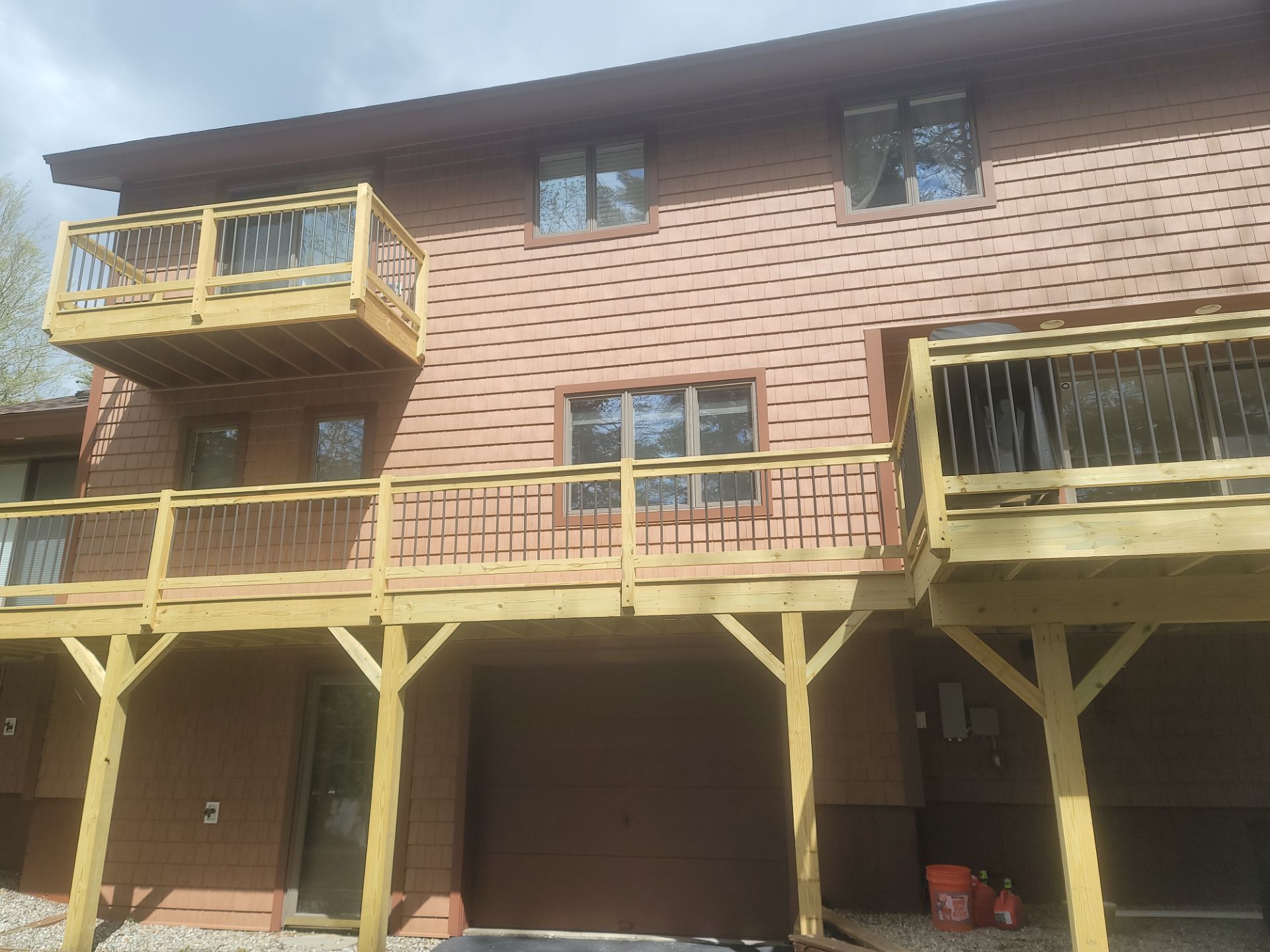 Two-story wooden house with raised decks and stairs under bright daylight