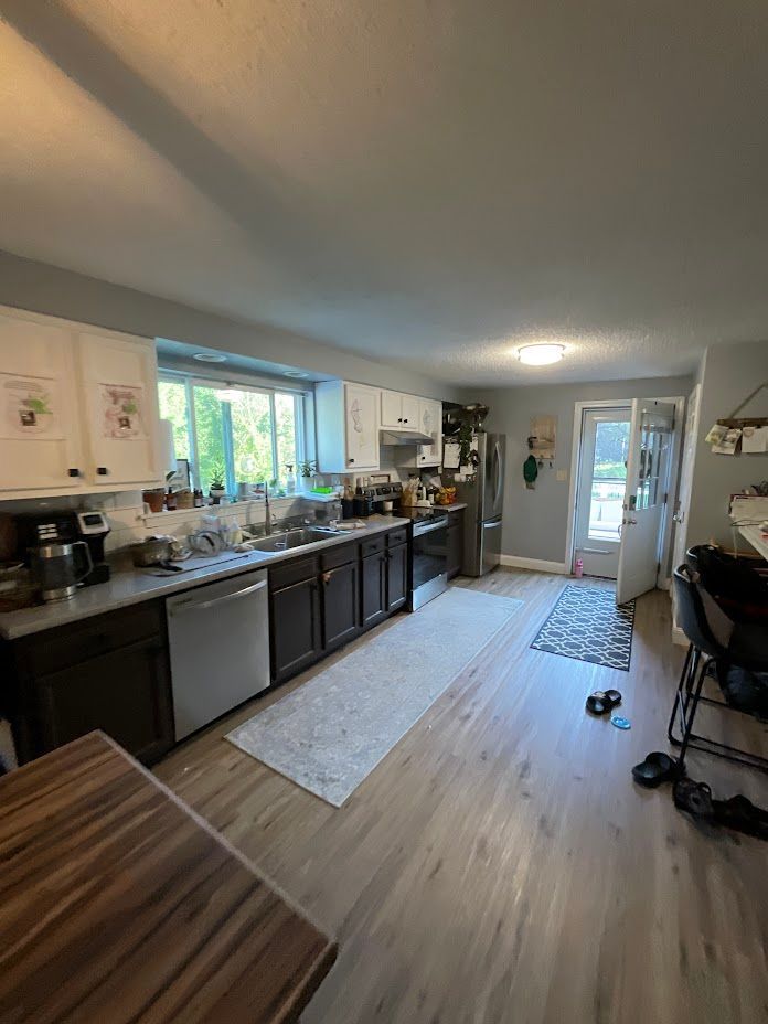 Bright kitchen with dark cabinets, wood floor, island, and sunlight through a window.