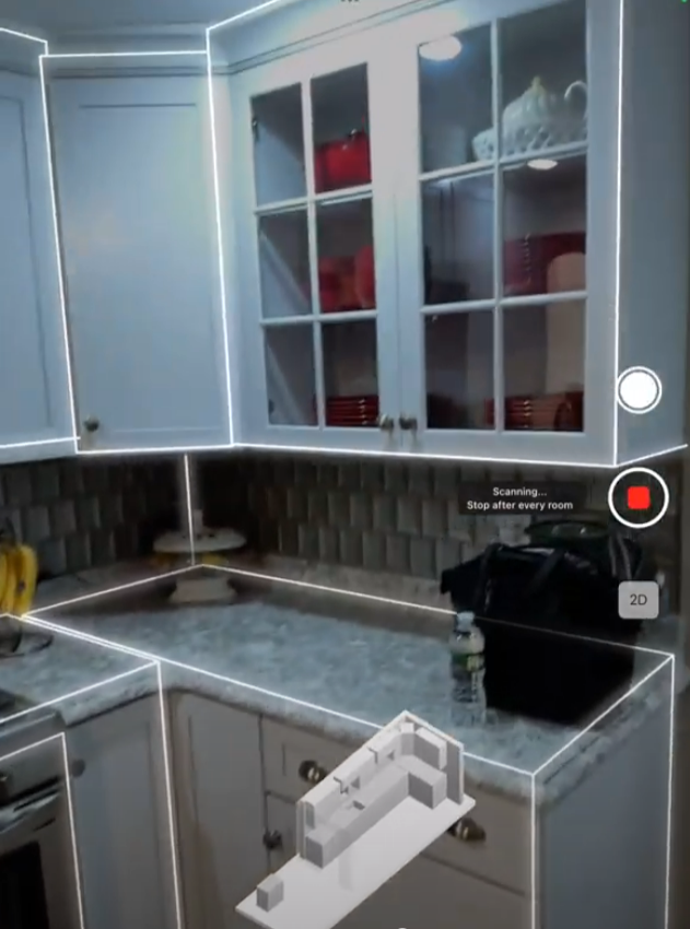 Gray kitchen with white cabinets, black countertop, and open shelves with red bowls and dishes.