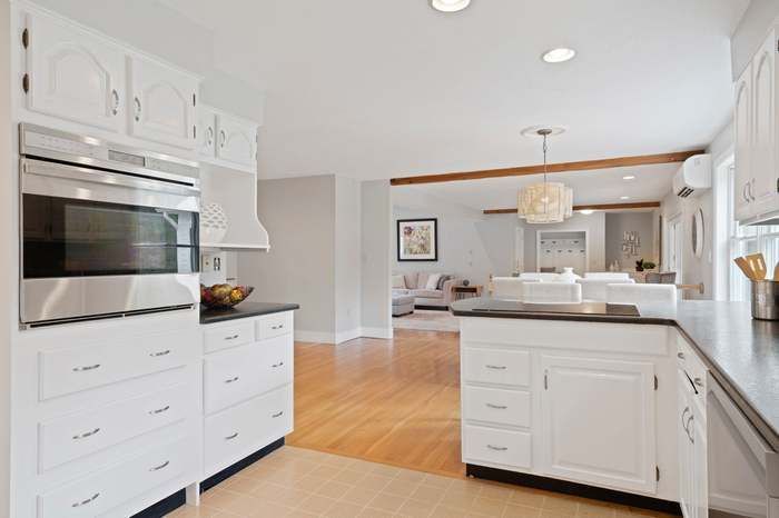Bright white kitchen with stainless appliances, island, and light wood floors