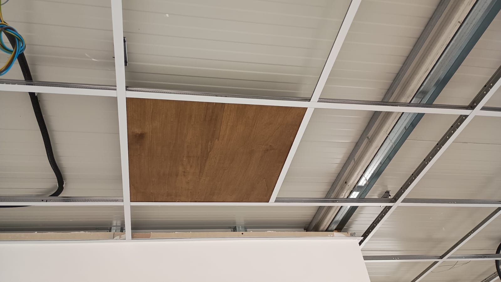 Griglia del soffitto con un pannello di compensato marrone che sostituisce una piastrella.