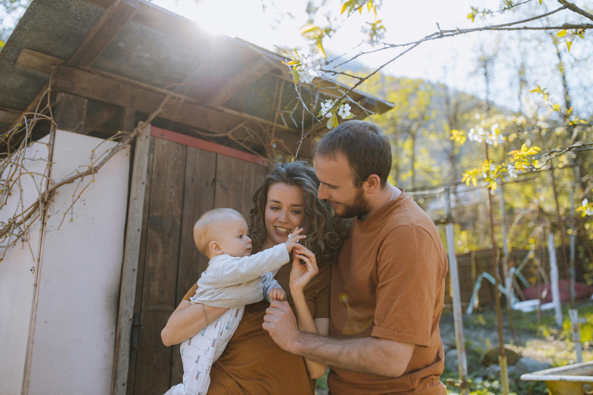 A man and a woman are kissing a baby on the cheek.