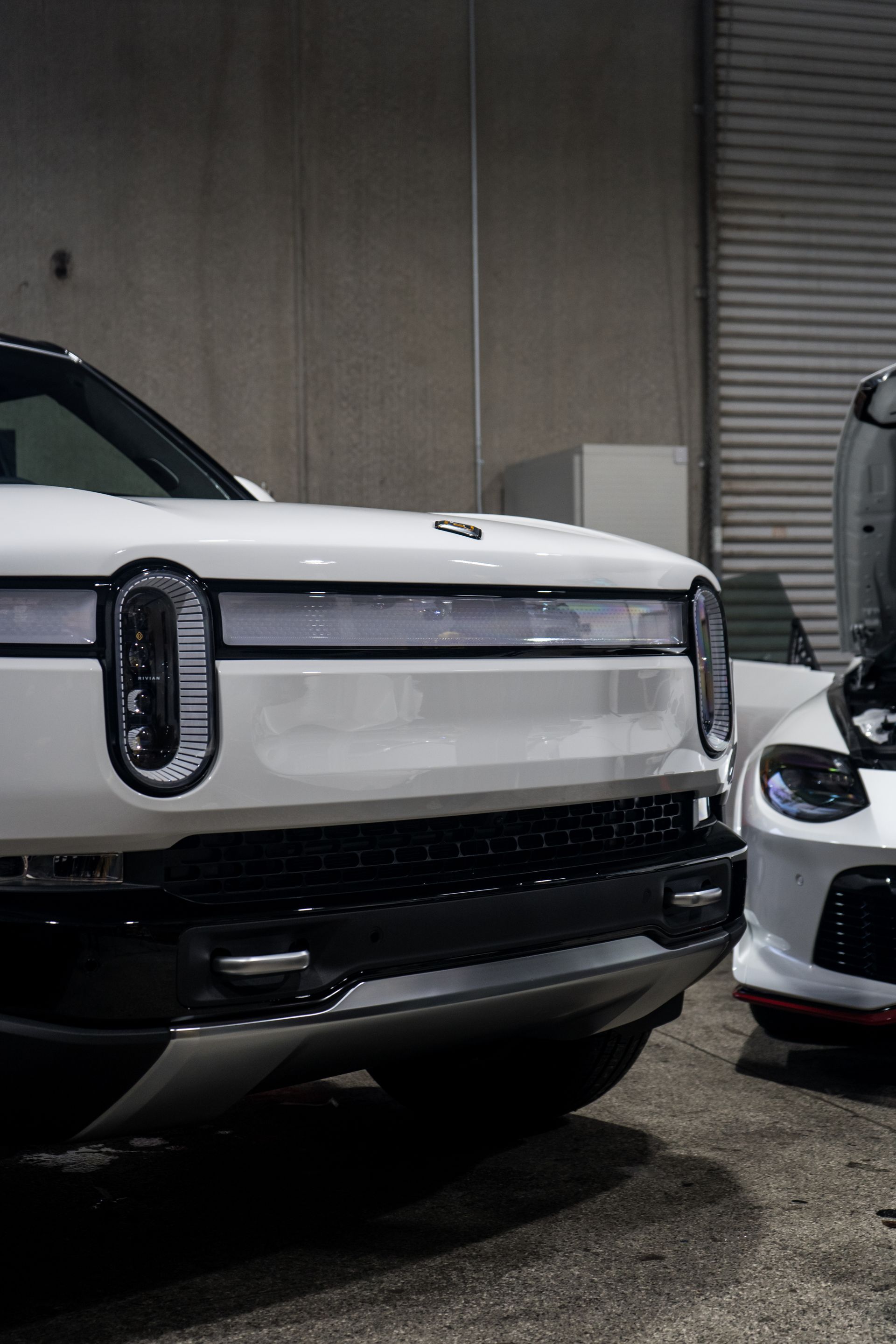 Two white cars are parked next to each other in a garage.