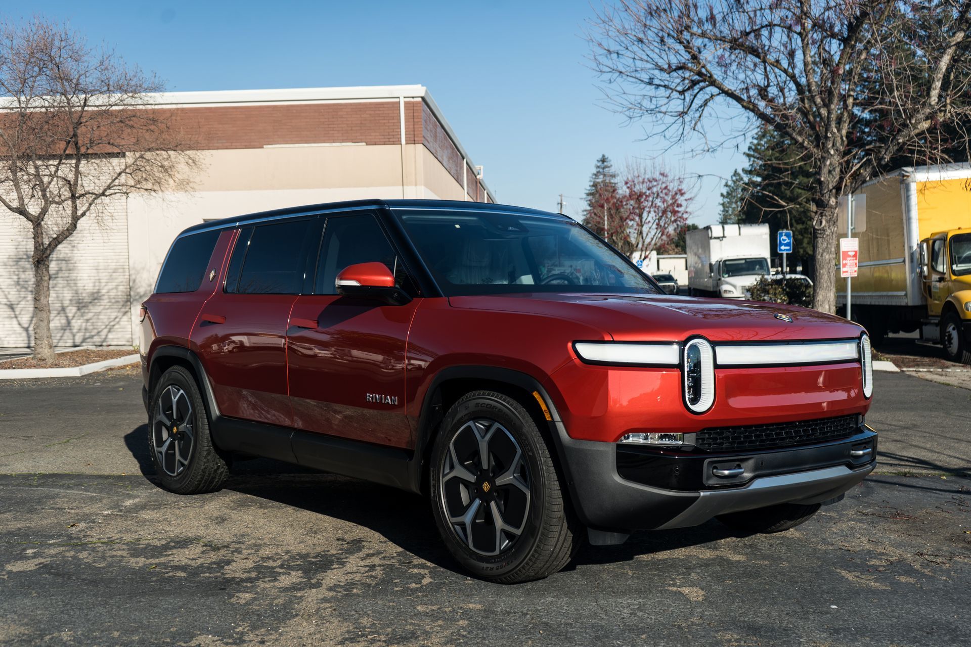 A red suv is parked in a parking lot in front of a building.