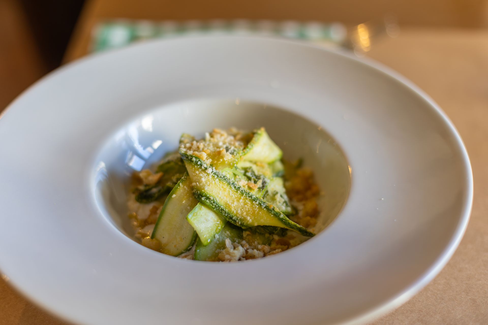 Zuppa gourmet con verdure servita in una ciotola bianca su un tavolo.