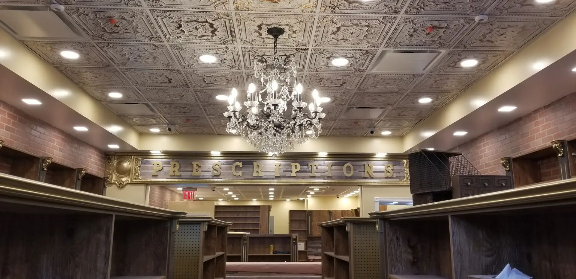 Empty ornate hall with chandelier, patterned tin ceiling, and dark wood booths or partitioned seating.