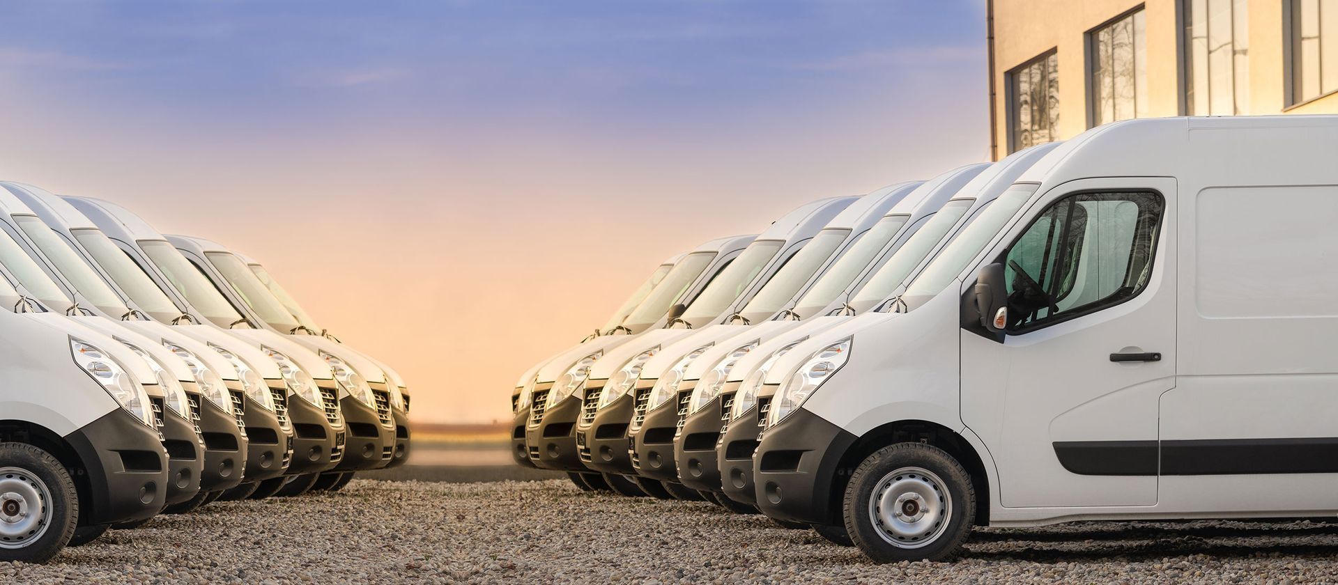 a row of white fleet vans parked in front of a building