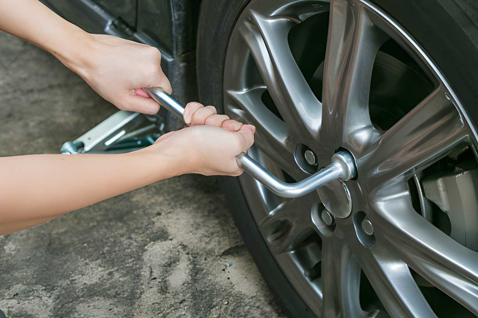 Hands using a wrench to tighten a car wheel lug nut