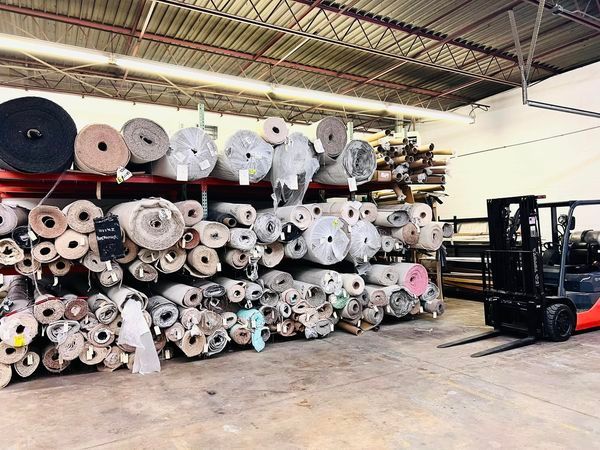 A forklift is moving rolls of fabric in a warehouse.