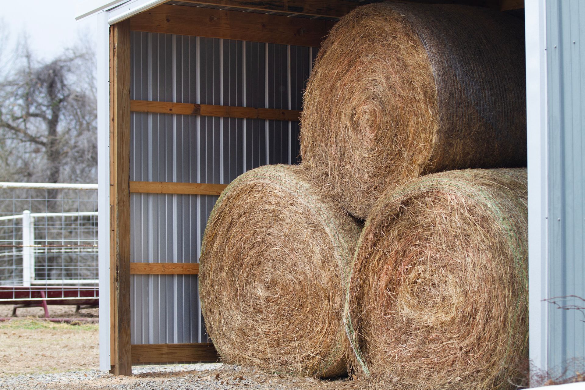 Stacking round bales using bulk net wrap for dry agricultural barn storage.