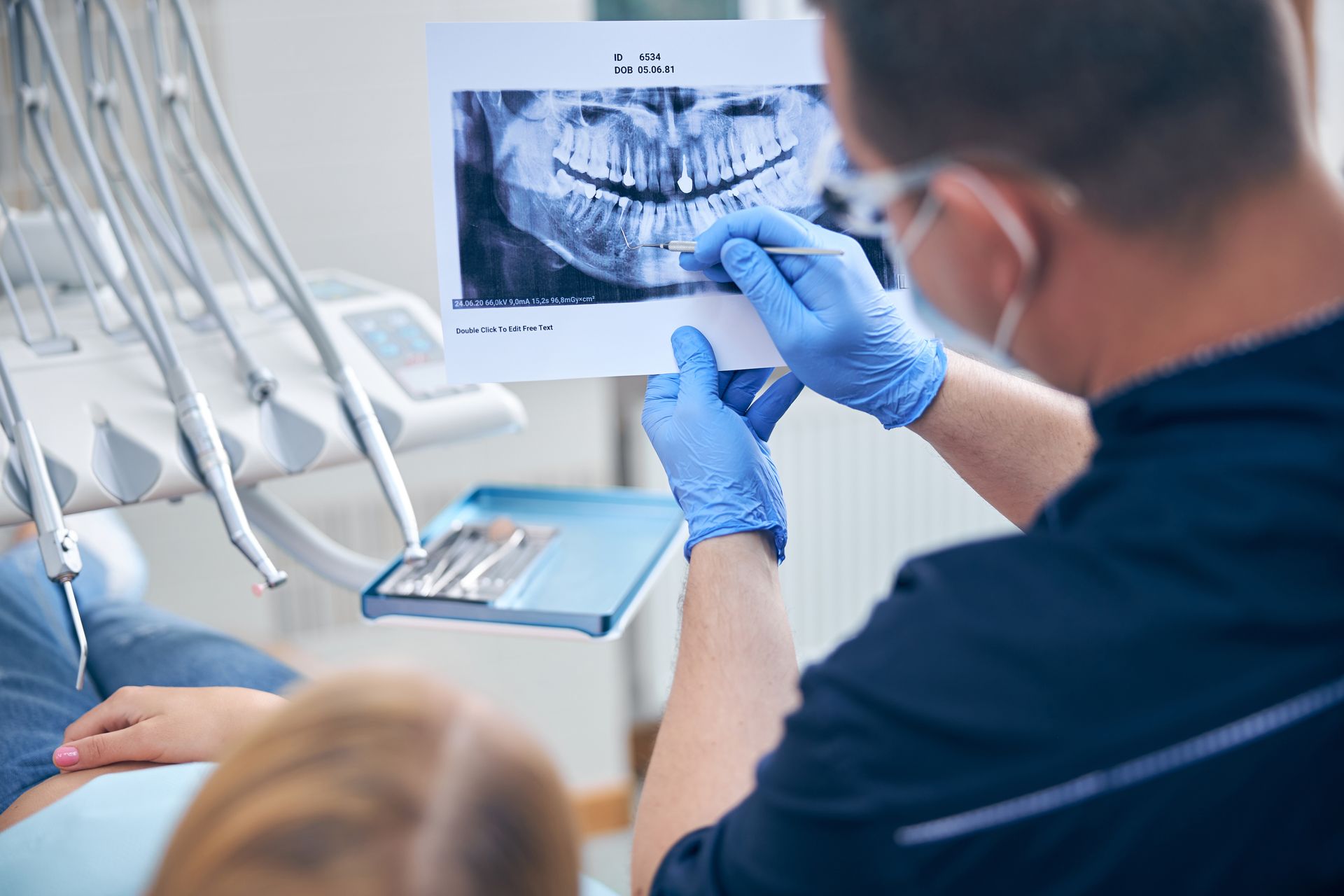 Surgeon discusses a woman's jaw X-ray with her during a medical consultation.