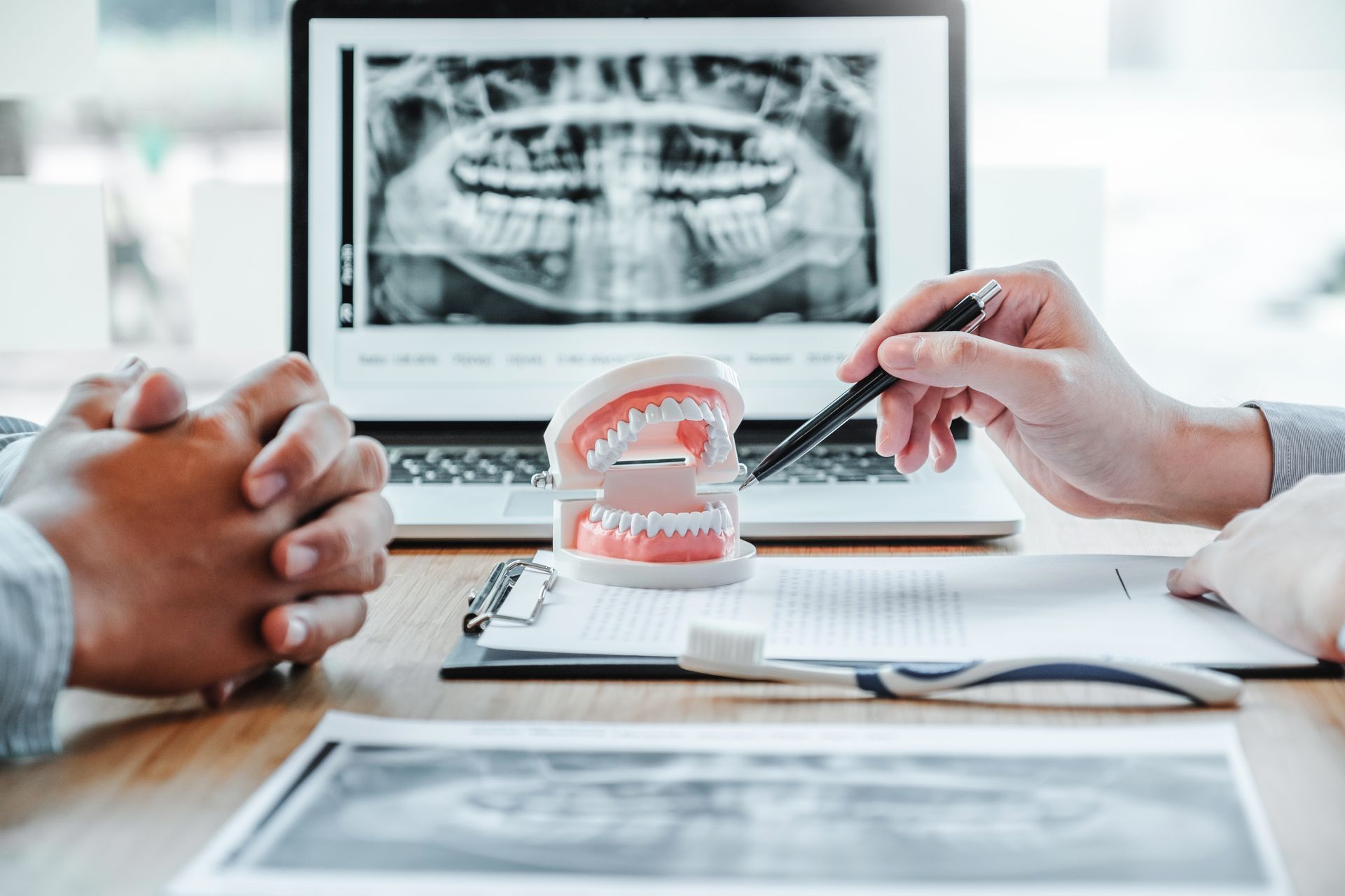 Dentist discusses dental problems with a male patient while reviewing an X-ray.
