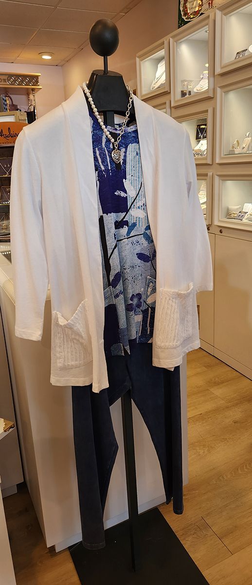 Clothing store display with layered blue-and-white top, white cardigan, and dark pants on a mannequin