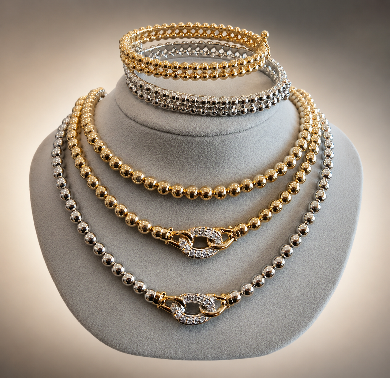 Gold and silver beaded necklaces displayed on a gray mannequin bust