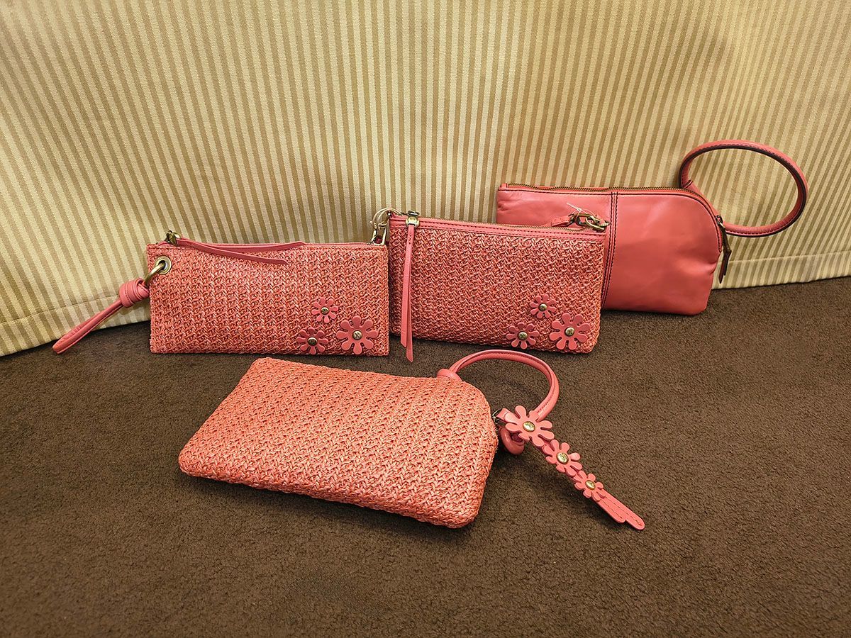 Four sparkly pink cosmetic bags and a matching wristlet on a brown surface