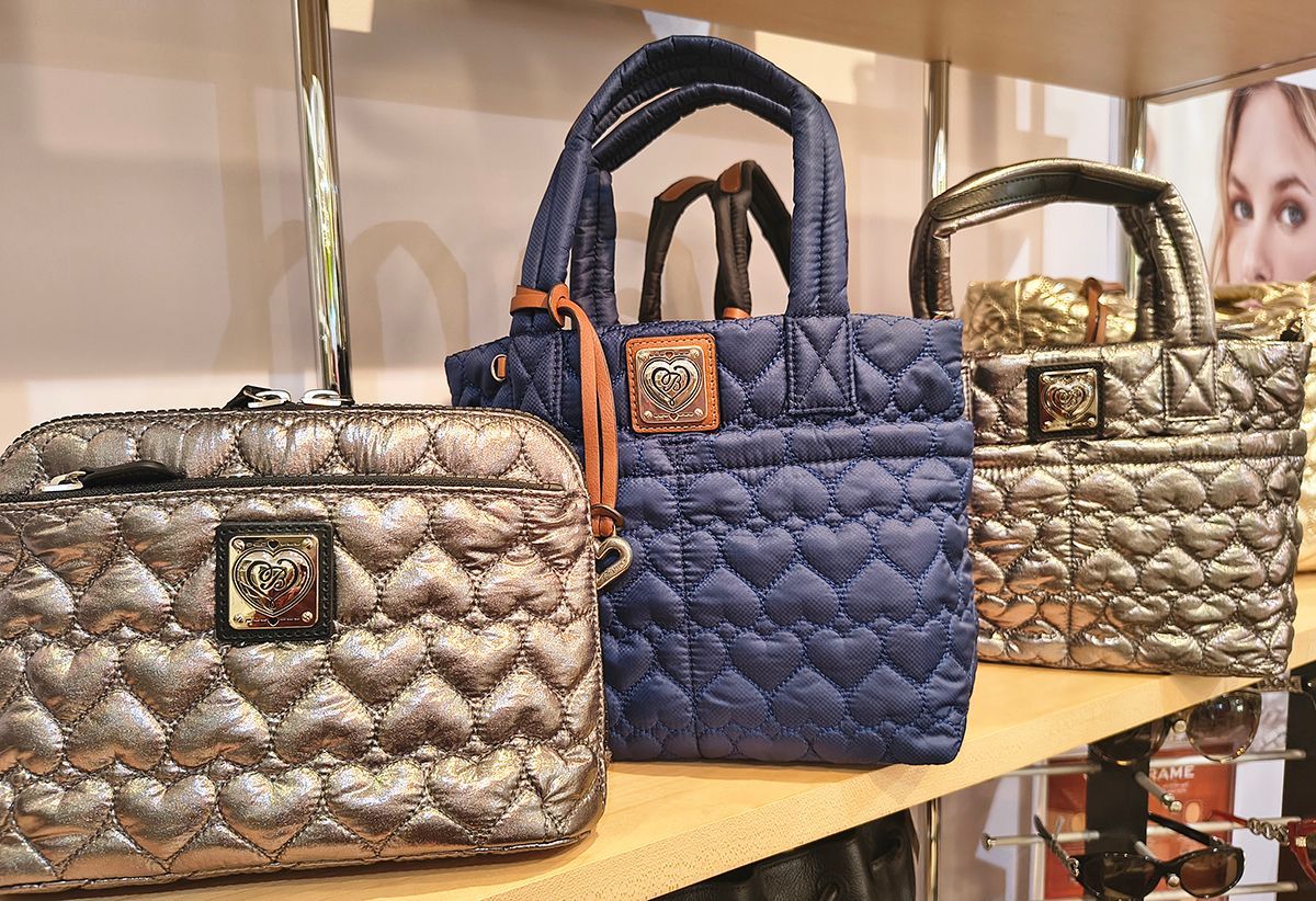 Three quilted handbags on a shelf: silver, navy, and gold with dark handles.