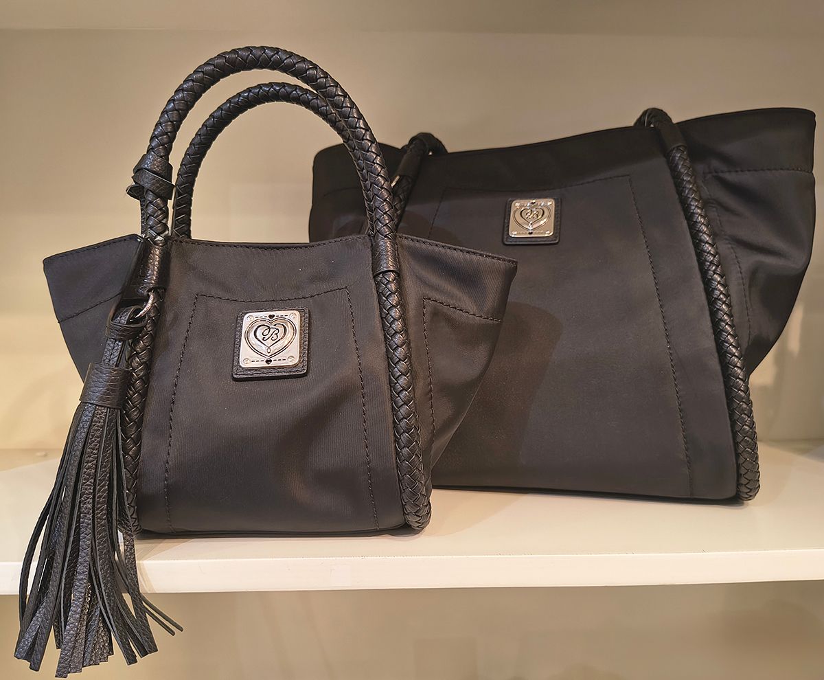 Two black handbags with decorative handles displayed on a shelf