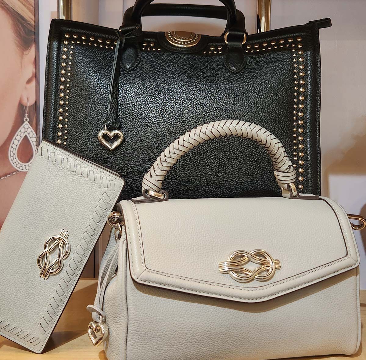 Three designer handbags in black and white with gold accents displayed together.