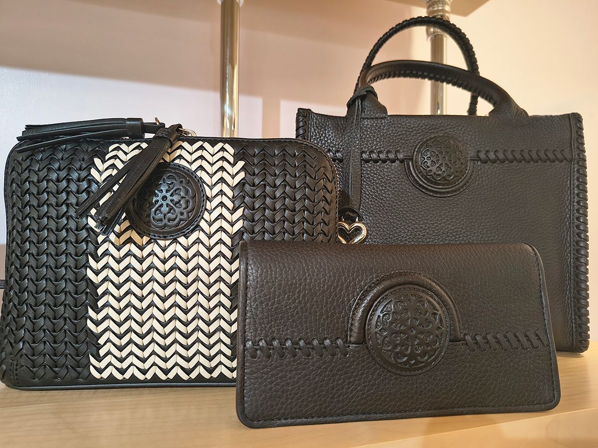 Three handbags and a wallet in black and beige chevron and textured black patterns on a table