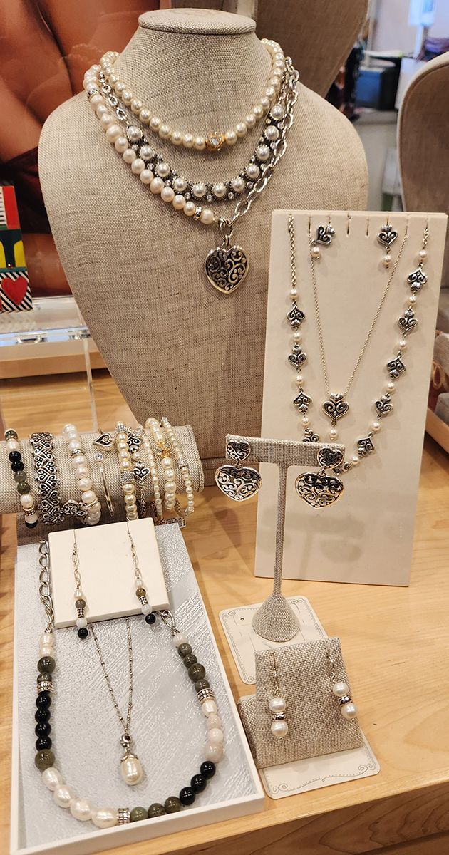 Jewelry display with layered silver necklaces, bracelets, earrings, and rings on a countertop