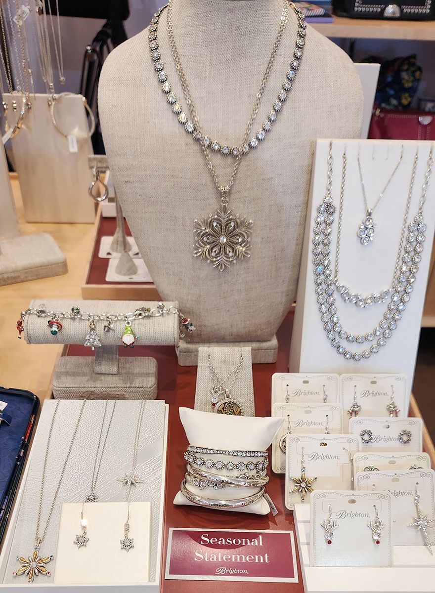 Jewelry display with silver and gold necklaces, bracelets, earrings, and rings on beige busts and stands