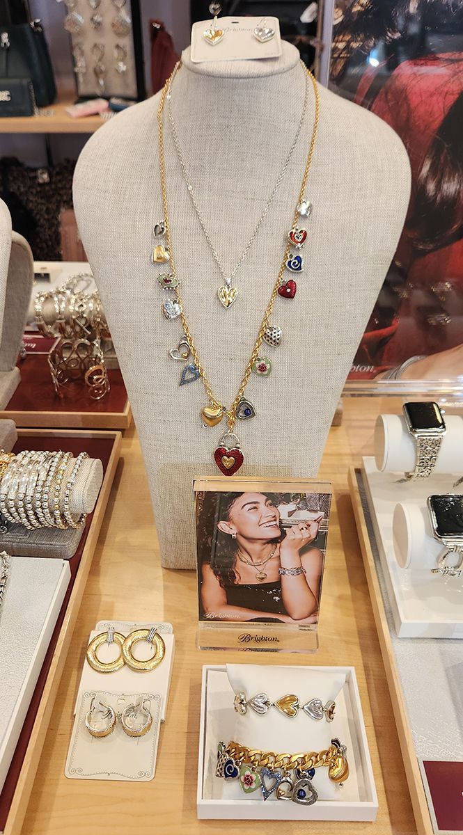 Jewelry display with layered necklaces on a mannequin bust and rings and bracelets on trays below