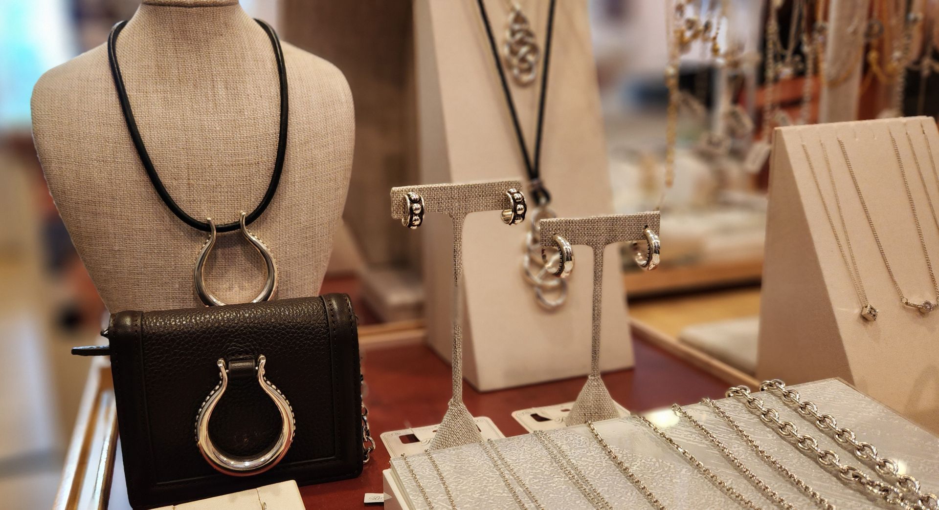 Display of jewelry on mannequins and stands, featuring necklaces, bracelets, and rings in gold, black, and beige.