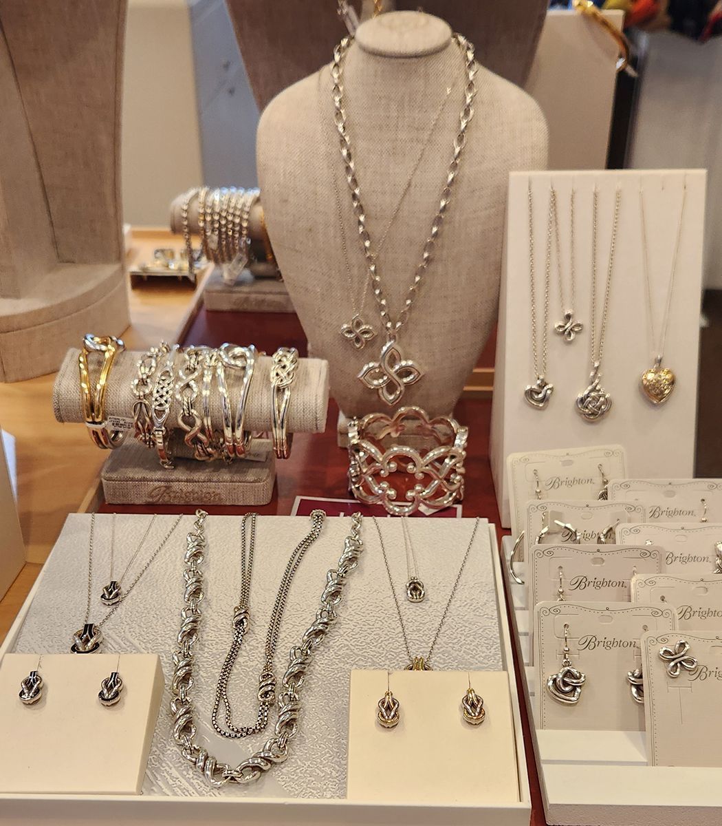 Jewelry display with necklaces, bracelets, and earrings on beige stands and trays