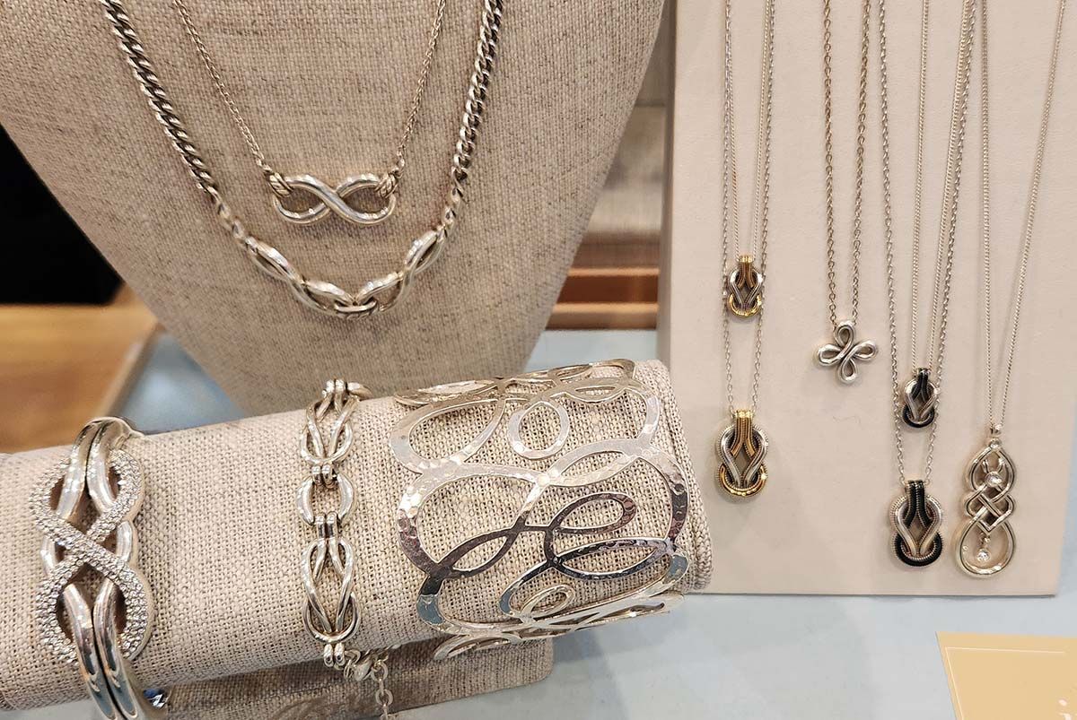 Gold necklaces and bracelets with gemstone pendants displayed on a beige necklace bust and white background.
