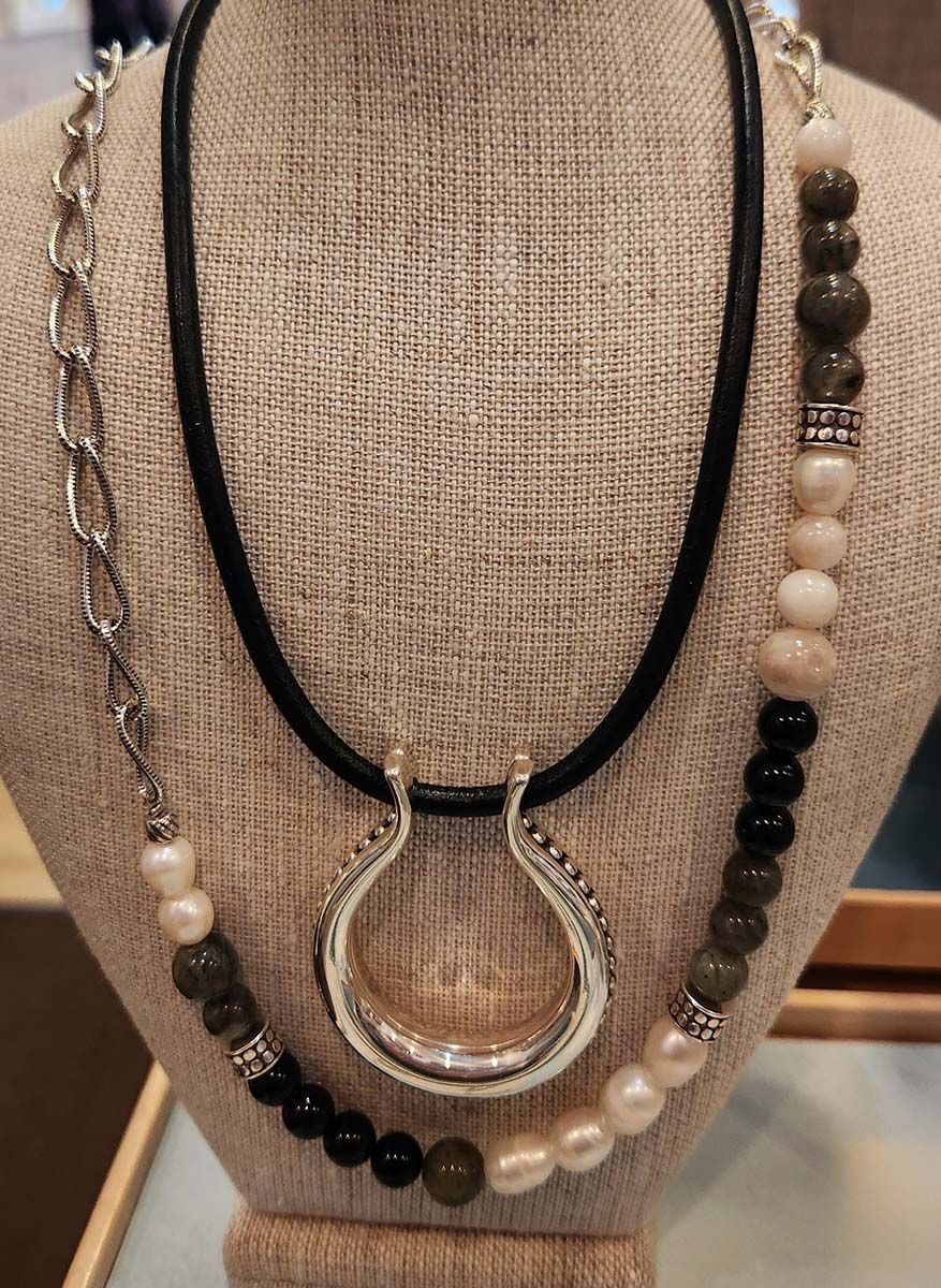 Black and beaded necklaces displayed on a tan bust form