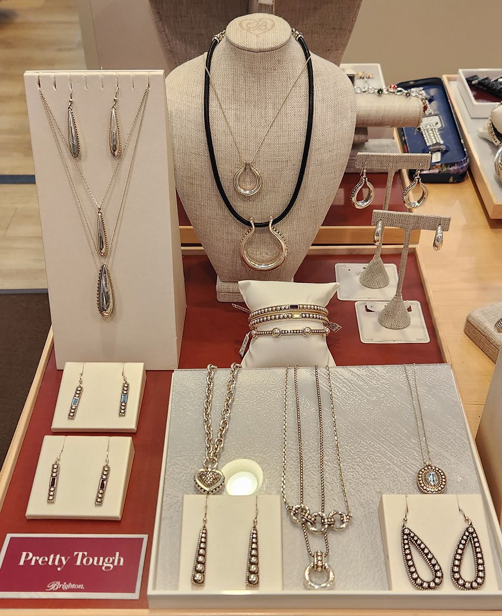 Jewelry display with silver necklaces, earrings, and bracelets on white stands and busts