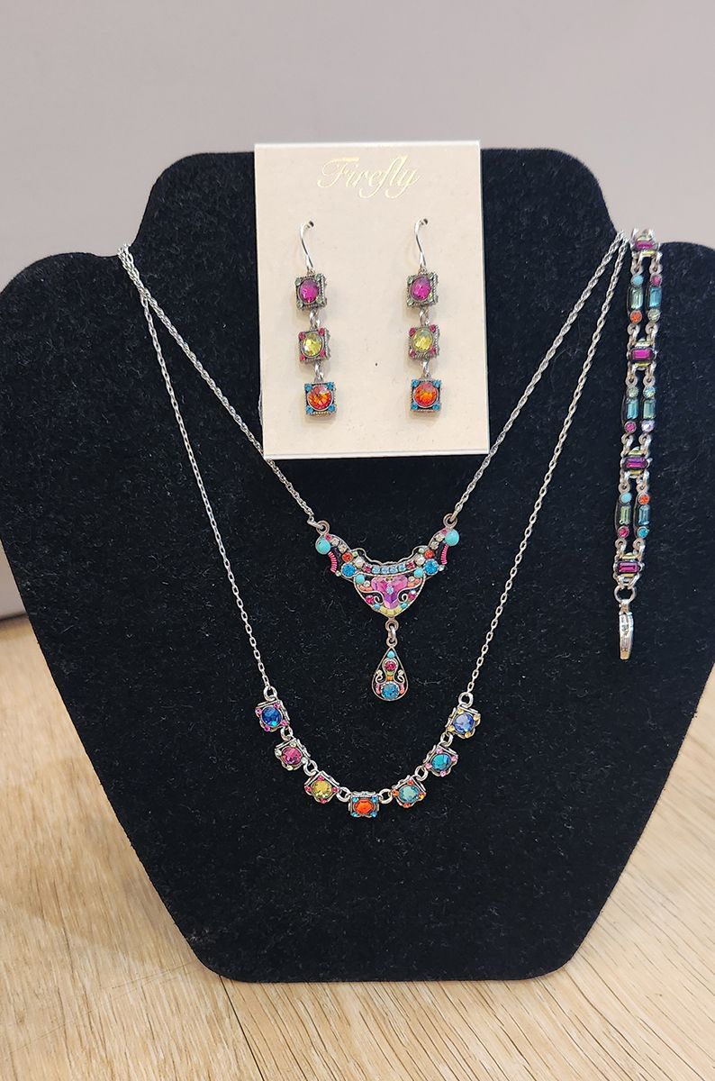 Jewelry display with colorful necklace, earrings, and bracelet on a black bust stand