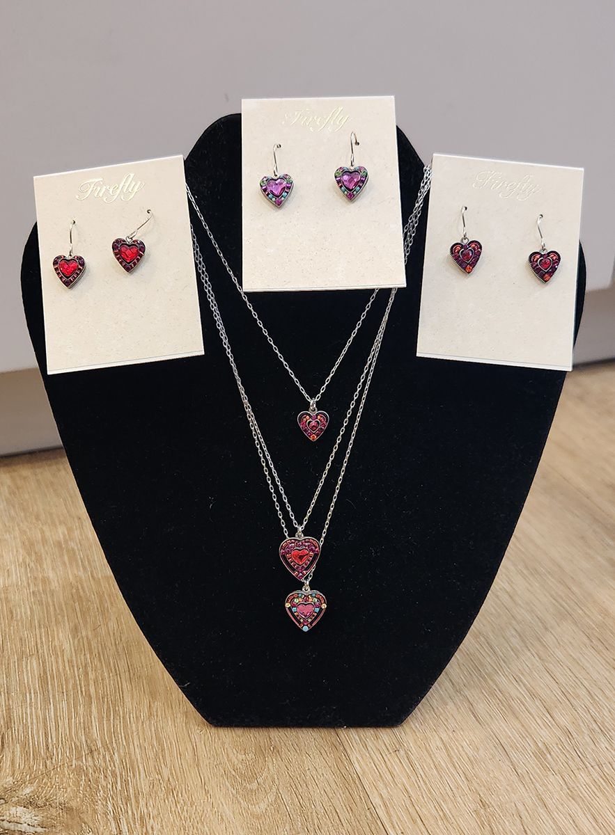 Jewelry display with heart-shaped earrings and matching necklaces on a black stand