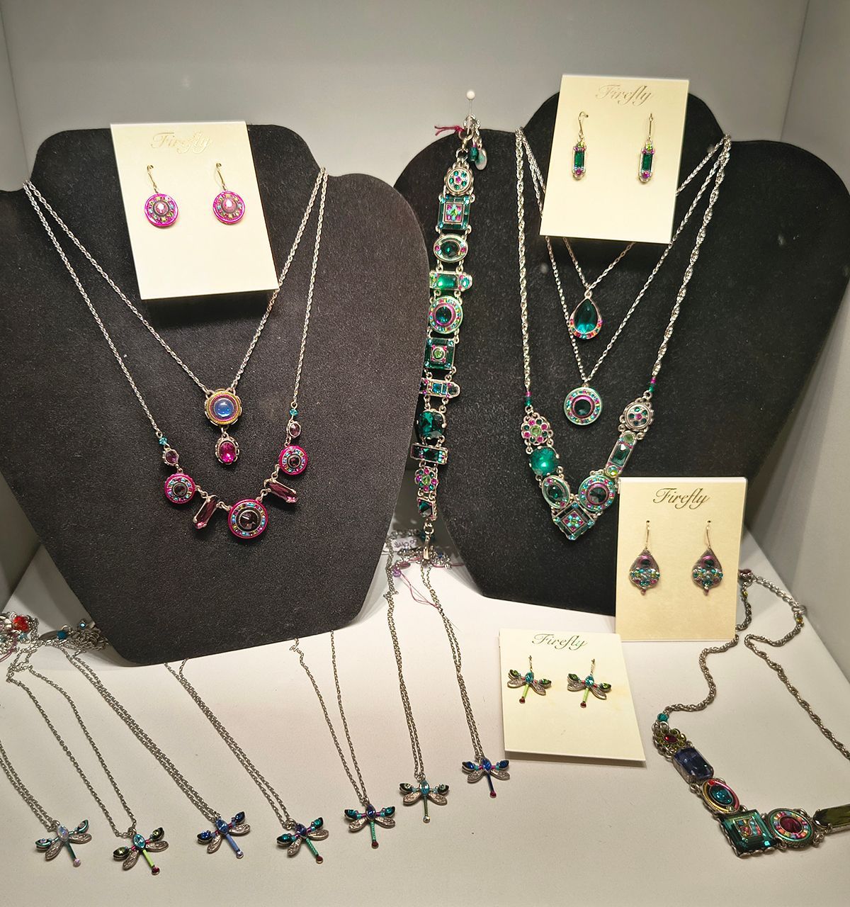 Jewelry display with colorful gemstone necklaces, earrings, and bracelets on black stands and white cards.