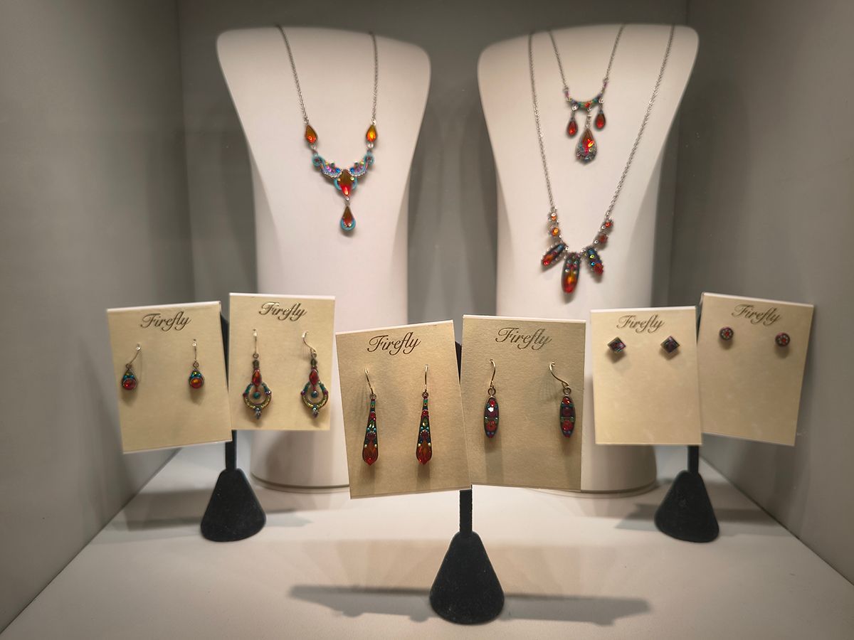 Jewelry display with colorful necklace and earring sets on white and beige stands
