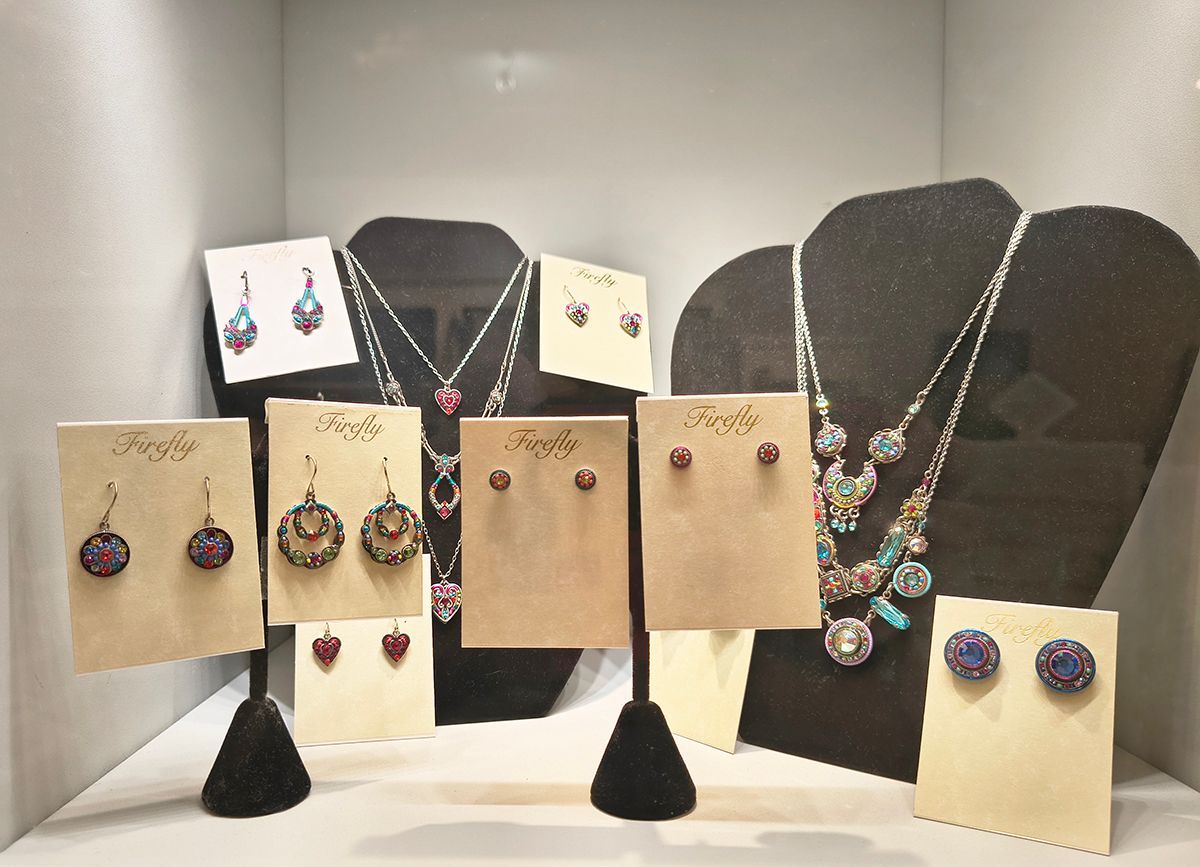 Jewelry display with earrings and necklaces on cream cards and black busts in a shop showcase