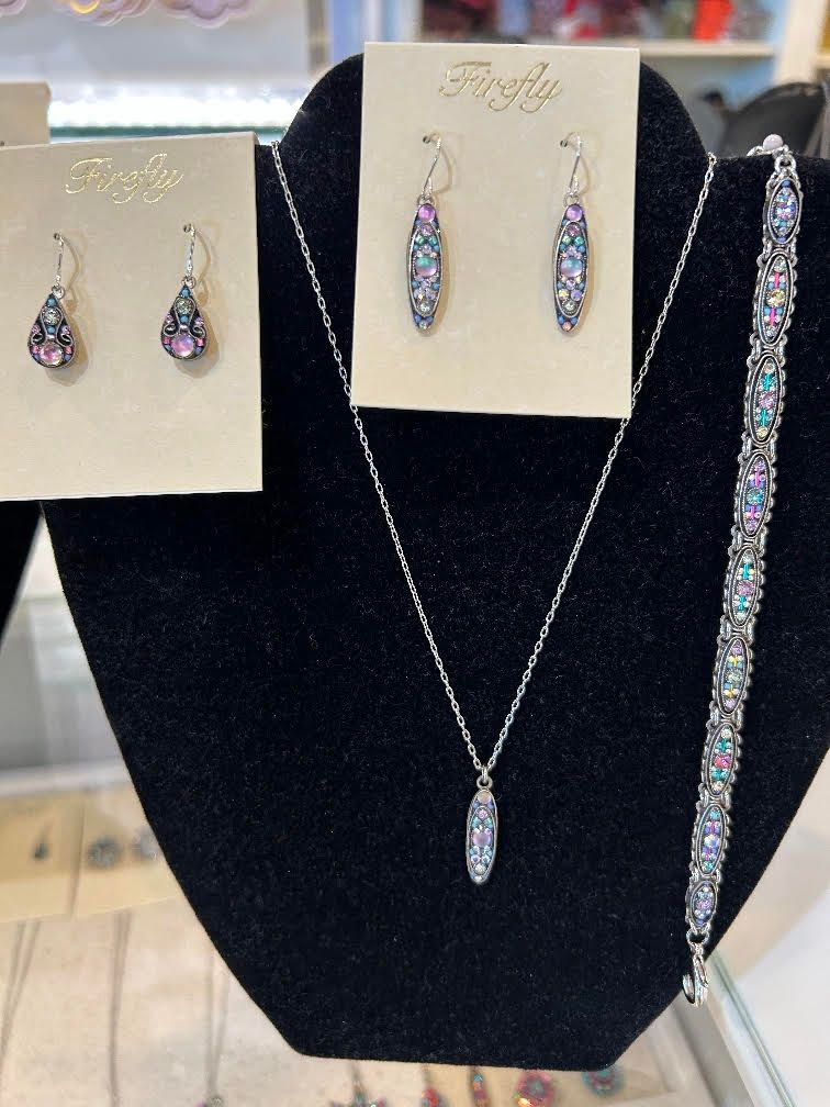 Jewelry display with multicolored crystal earrings, necklace, and bracelet on black and cream stands