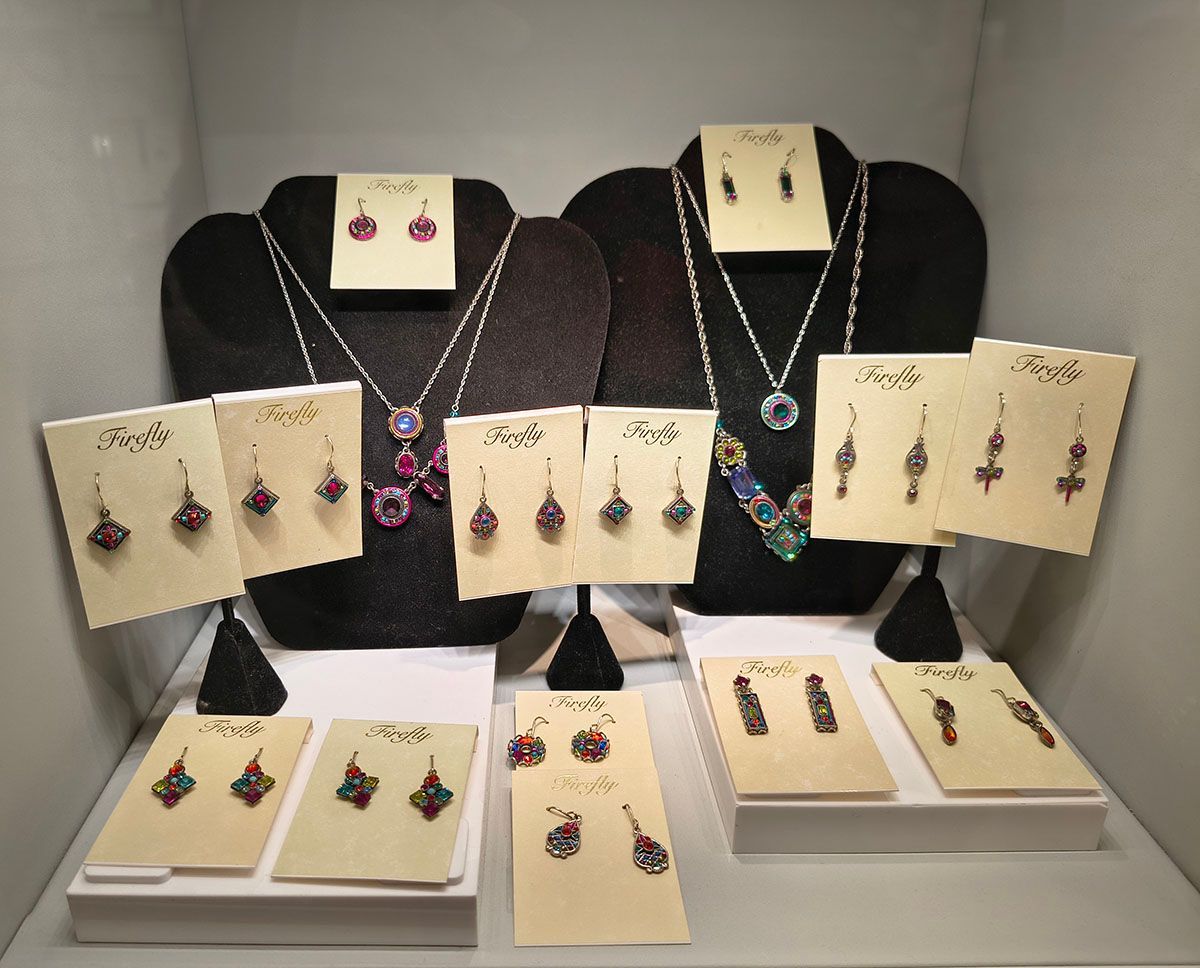 Jewelry display with earrings and necklaces on black busts and cream stands