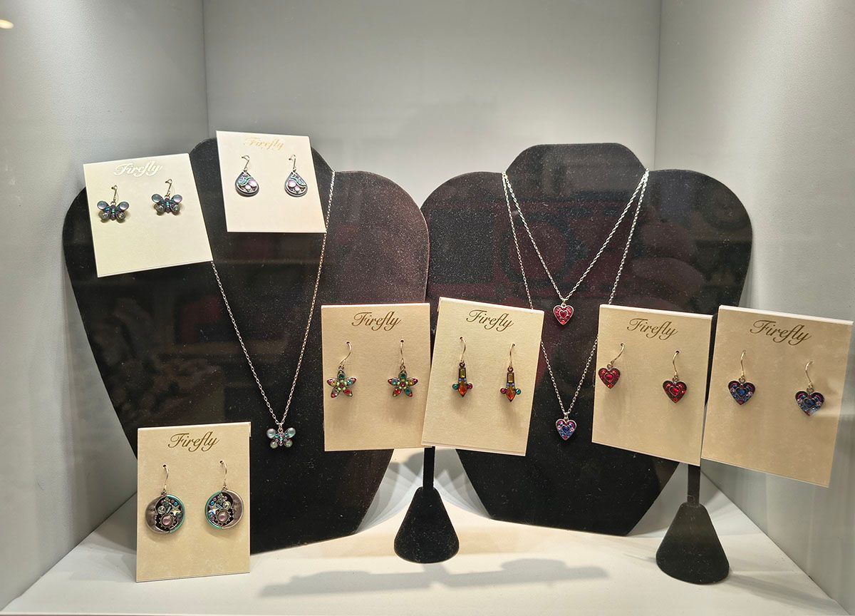 Jewelry display with earrings and necklaces on black stands against a light backdrop