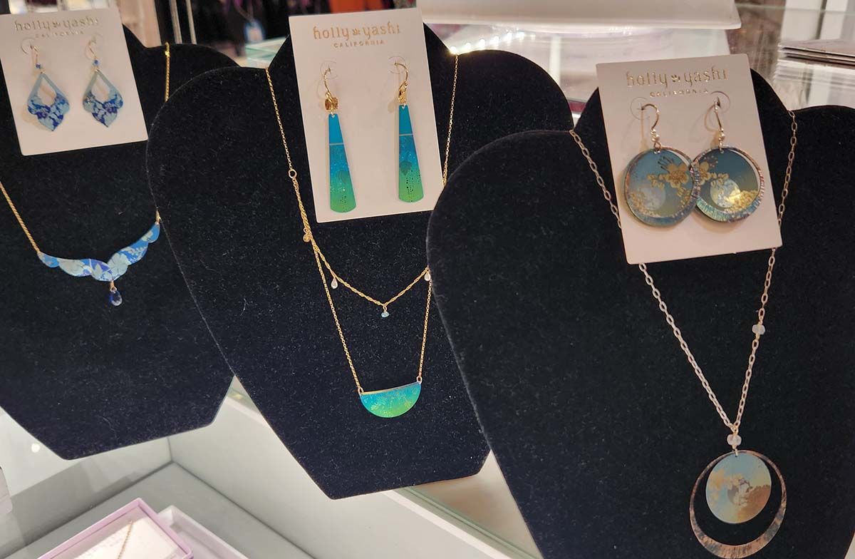 Display of blue and silver jewelry on black stands, including necklaces, earrings, and a pendant.