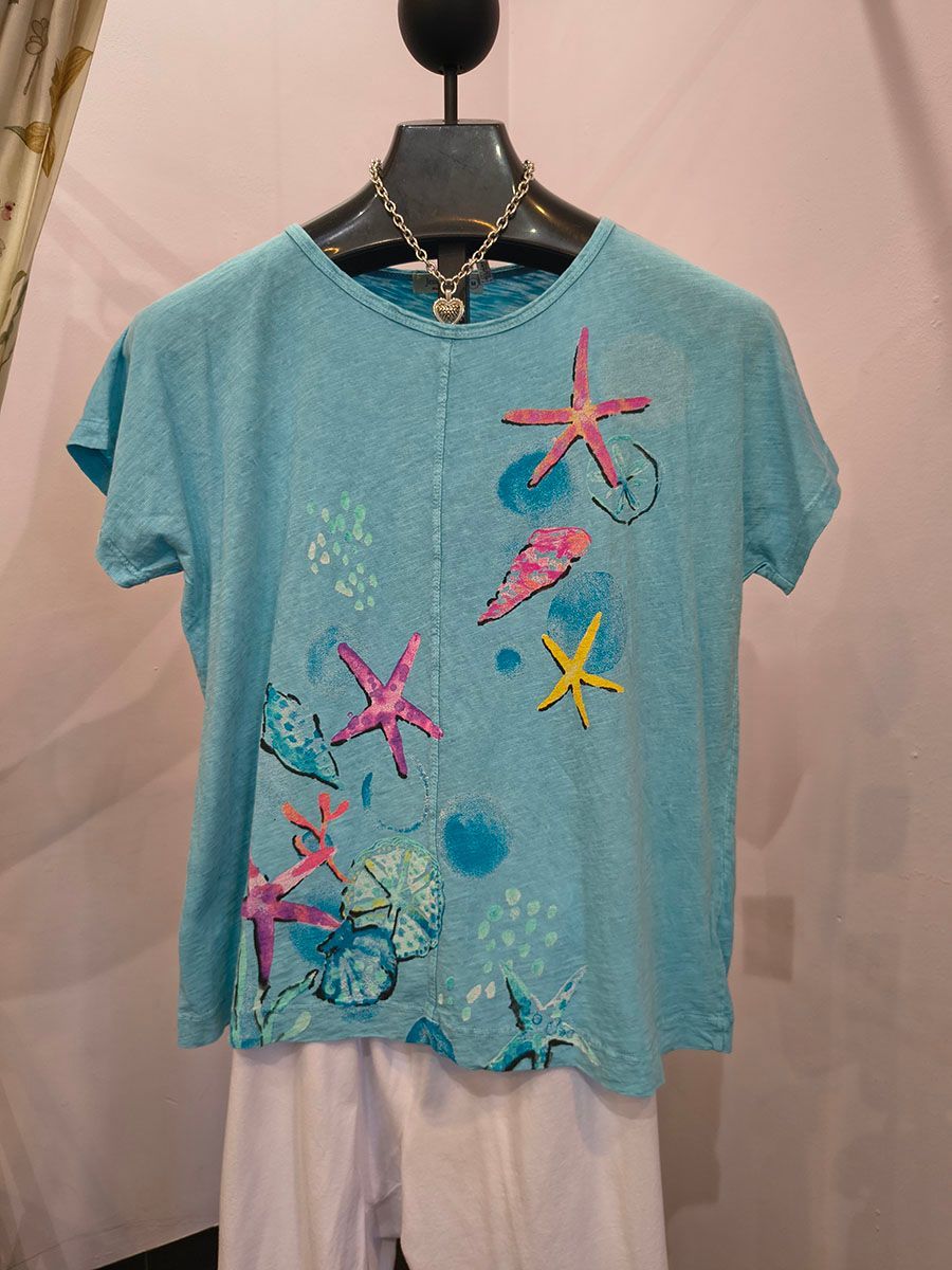 Blue starfish-print T-shirt hanging on a mannequin in a clothing display.