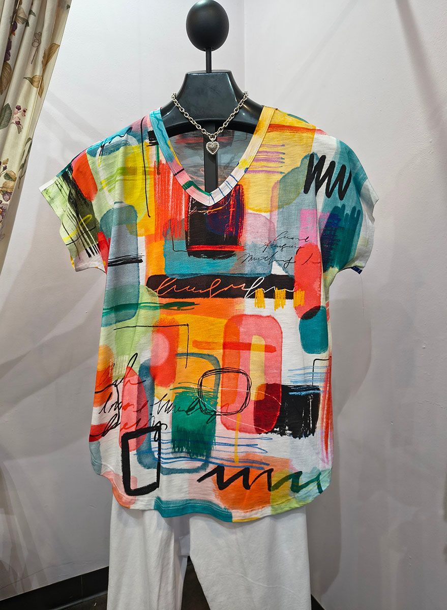 Colorful abstract patterned T-shirt on a mannequin against a light backdrop.